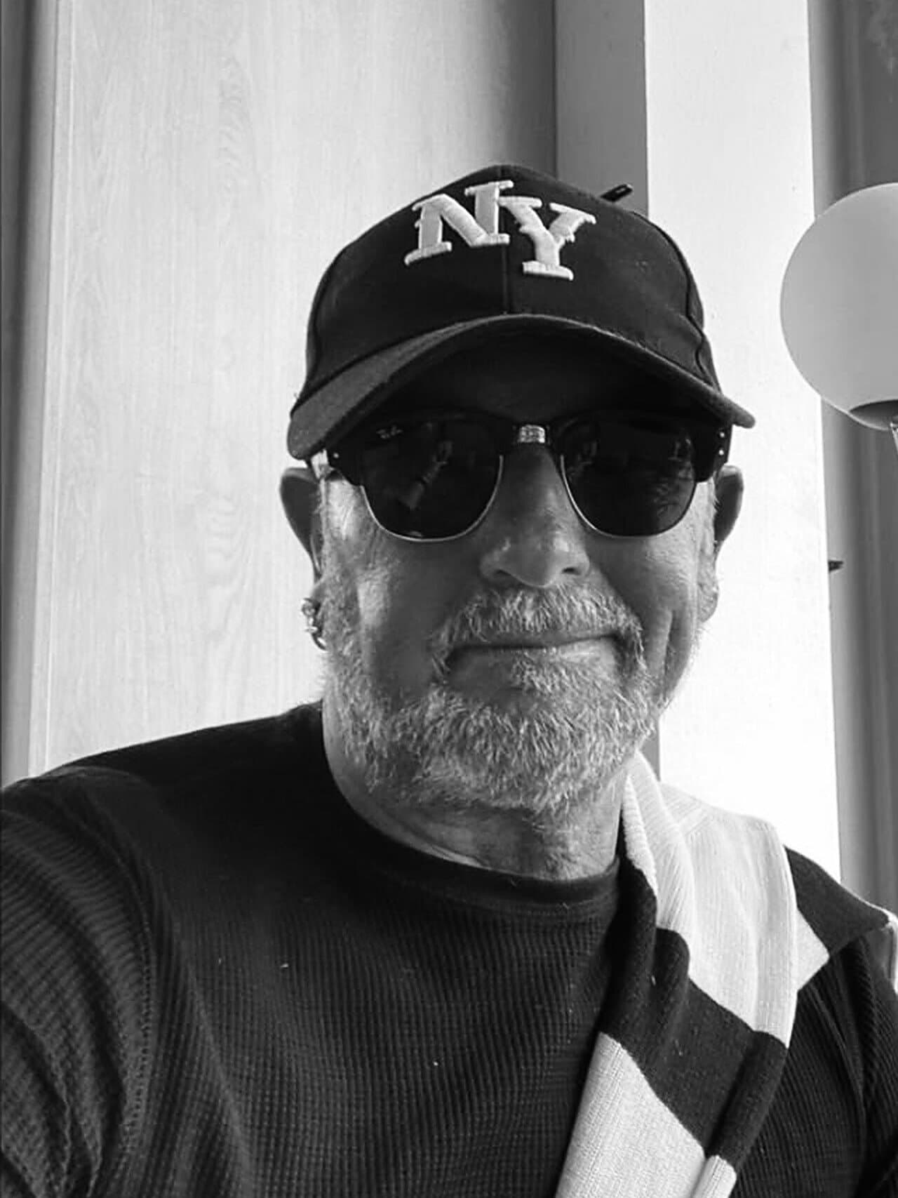 Adam Dzielak mit Kappe und Sonnenbrille am Fenster, Schwarzweiss